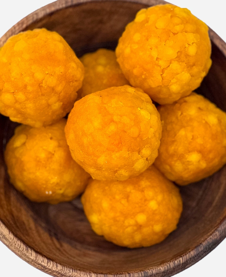 Close-up of handmade golden boondi ladoo, pearls of gram flour bound in syrup.