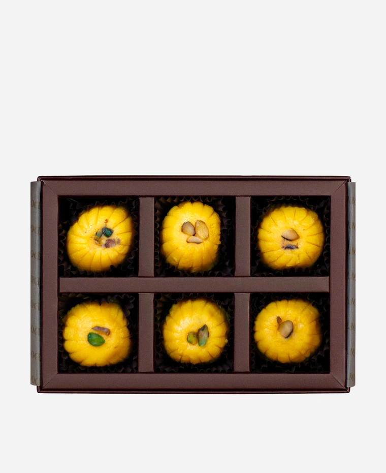 Kesar Peda gift box, 6 pieces, open: saffron-gold kesar peda finished with pistachio in a burgundy box with gold foil lettering.
