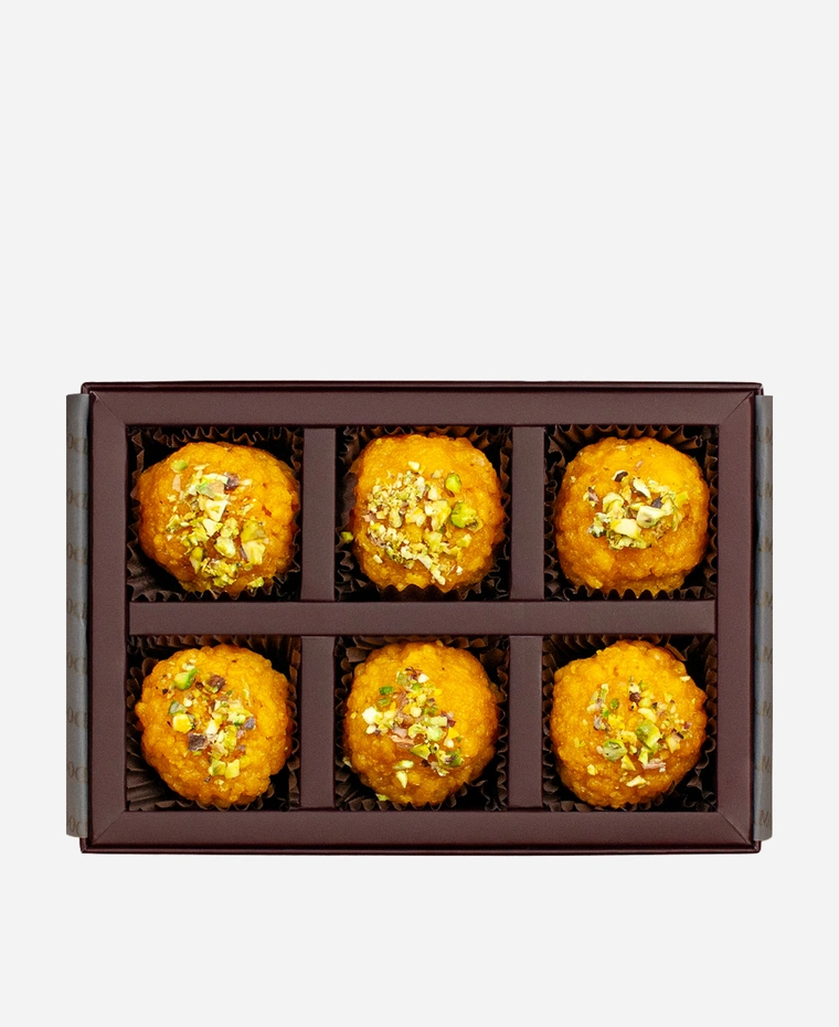 Pistachio Boondi Ladoo gift box, 6 pieces, open: golden boondi ladoo topped with chopped pistachio in a burgundy box with gold foil lettering.