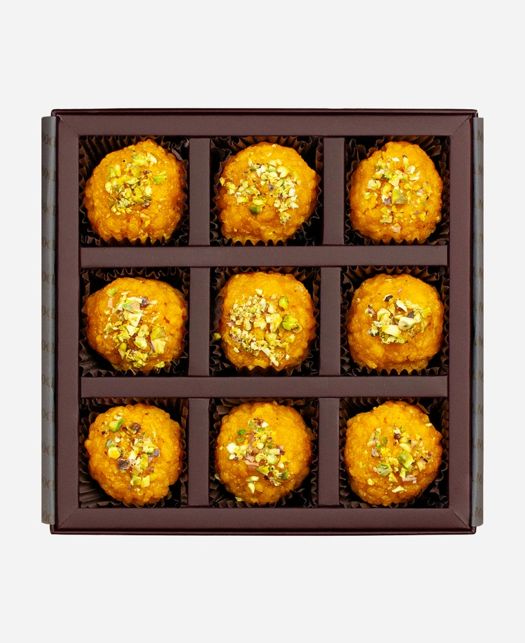 Pistachio Boondi Ladoo gift box, 9 pieces, open: golden boondi ladoo topped with chopped pistachio in a burgundy box with gold foil lettering.