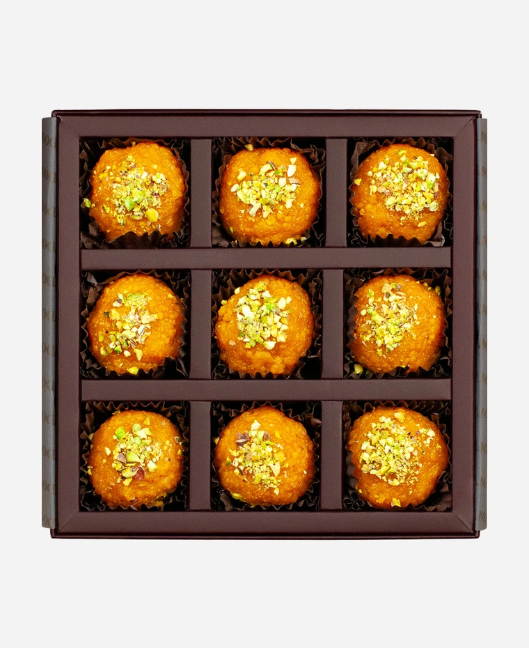 Pistachio Motichoor Ladoo gift box, 9 pieces, open: fine-grained motichoor ladoo topped with chopped pistachio in a burgundy box with gold foil lettering.