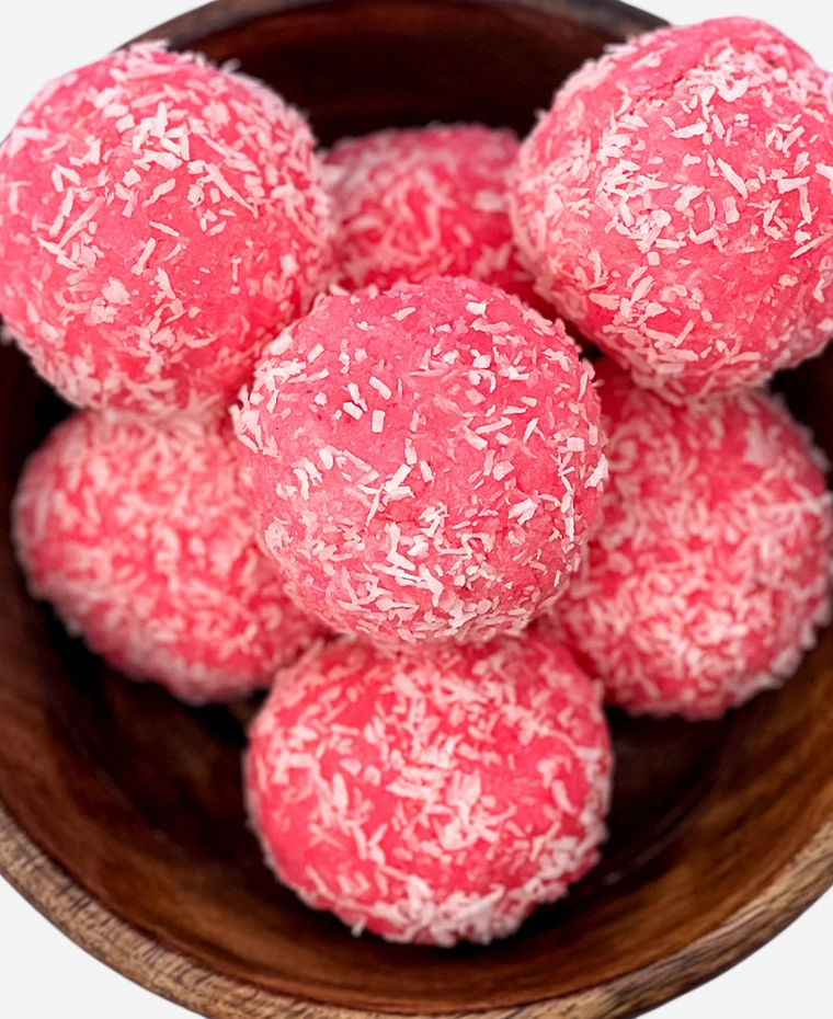 Close-up of handmade pink rose coconut ladoo rolled in desiccated coconut.