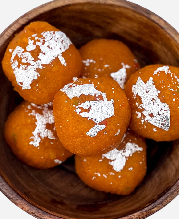 Close-up of handmade fine-grained motichoor ladoo topped with edible silver leaf.