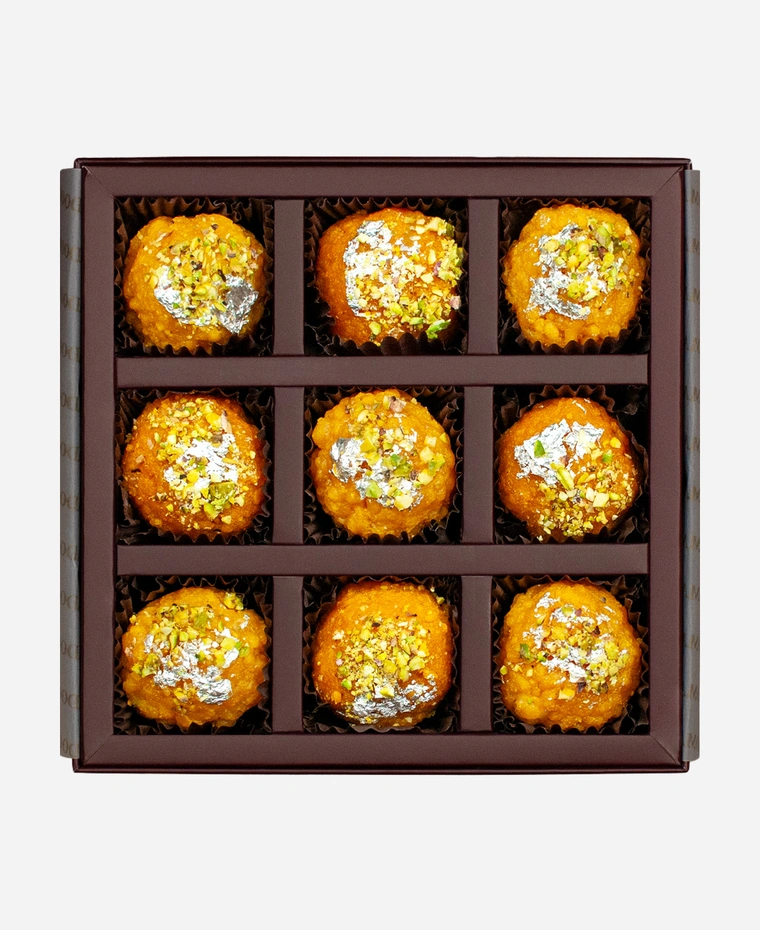 Silver Leaf & Pistachio Ladoo Selection gift box, 9 pieces, open: boondi and motichoor ladoo topped with edible silver leaf and chopped pistachio in a burgundy box with gold foil lettering.