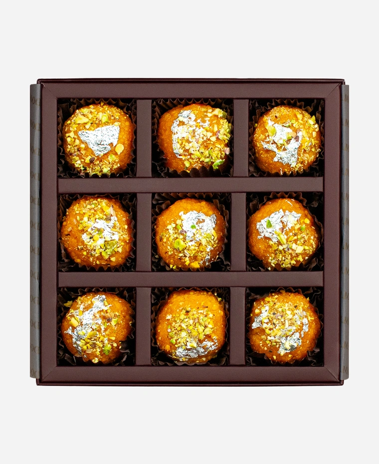 Silver Leaf & Pistachio Motichoor Ladoo gift box, 9 pieces, open: fine-grained motichoor ladoo topped with edible silver leaf and chopped pistachio in a burgundy box with gold foil lettering.