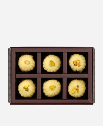 Khoya Peda gift box, 6 pieces, open: ivory khoya peda finished with pistachio in a burgundy box with gold foil lettering.