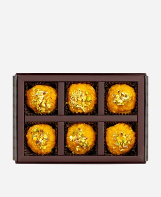 Pistachio Boondi Ladoo gift box, 6 pieces, open: golden boondi ladoo topped with chopped pistachio in a burgundy box with gold foil lettering.