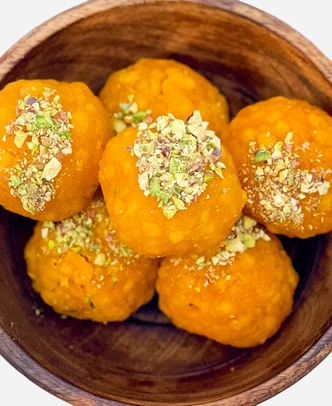 Close-up of handmade golden boondi ladoo topped with chopped pistachio.