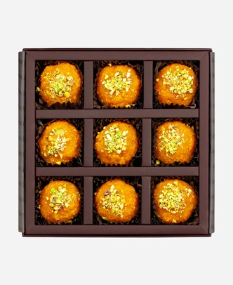 Pistachio Motichoor Ladoo gift box, 9 pieces, open: fine-grained motichoor ladoo topped with chopped pistachio in a burgundy box with gold foil lettering.