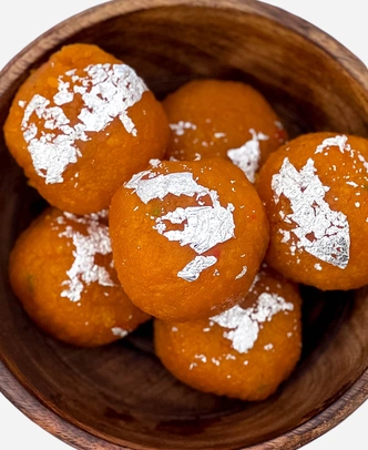 Close-up of handmade fine-grained motichoor ladoo topped with edible silver leaf.