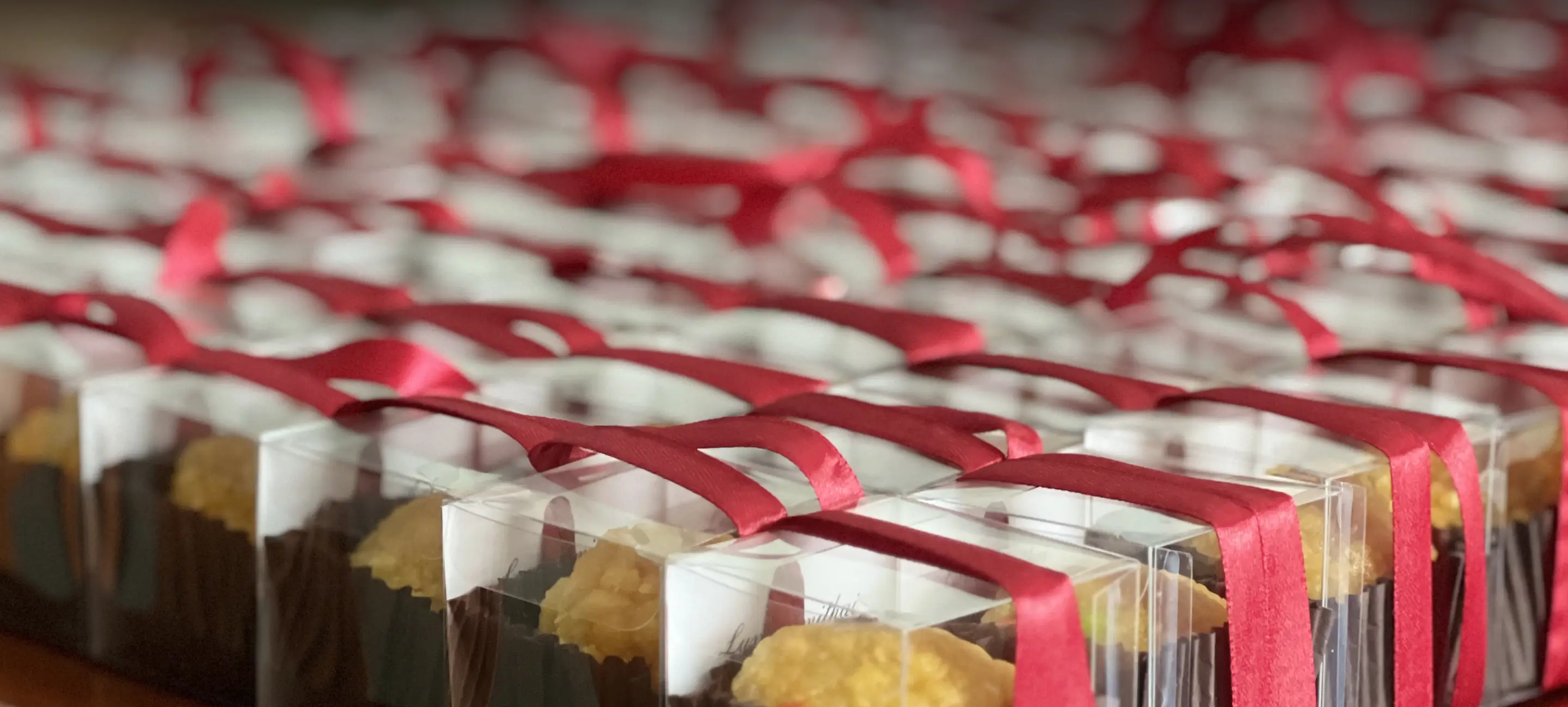 Ladoomail favour boxes tied with ruby red ribbon and filled with handmade ladoo.
