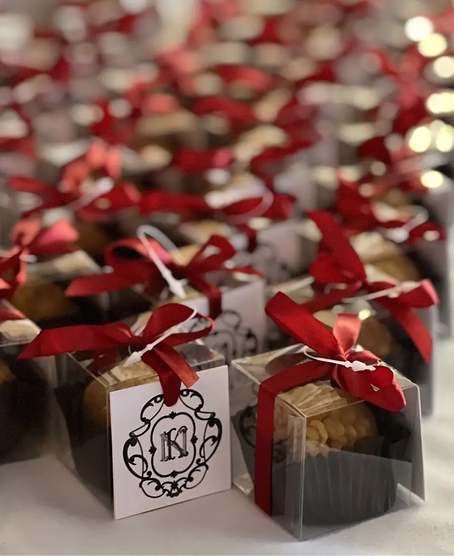 Rows of Ladoomail celebration favours with red ribbon bows and monogrammed swing tags.