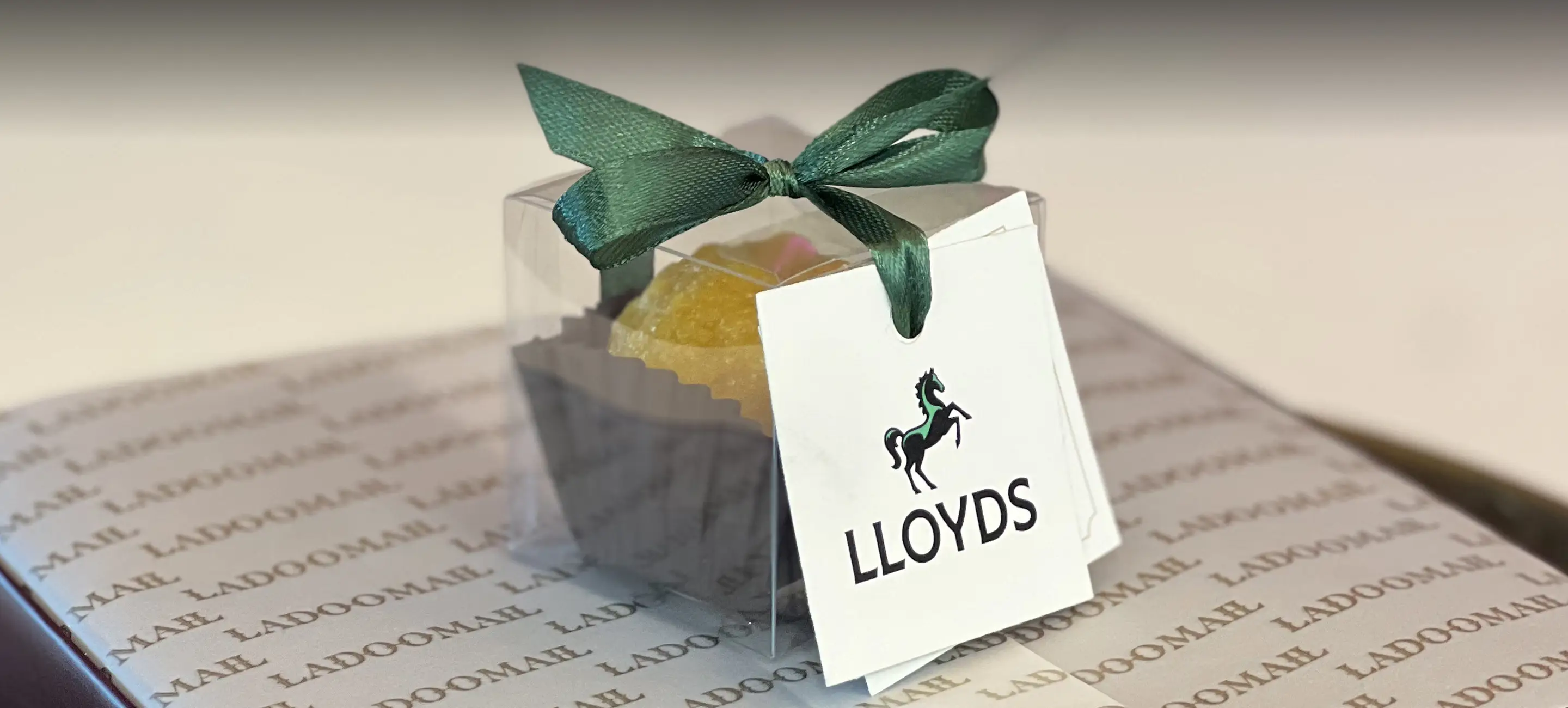 Ladoomail celebration favour with green ribbon and a Lloyds swing tag on Ladoomail airmail wrapping paper.