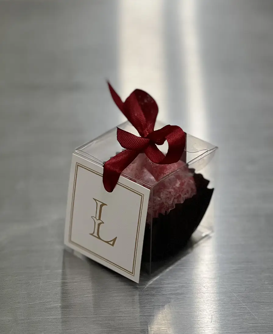 Ladoomail gift box with a red ribbon bow and a monogrammed swing tag.