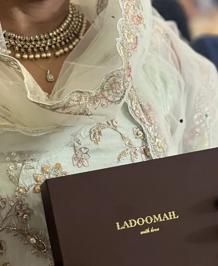 Cream bridal dupatta beside a burgundy Ladoomail gift box inscribed 'with love'.