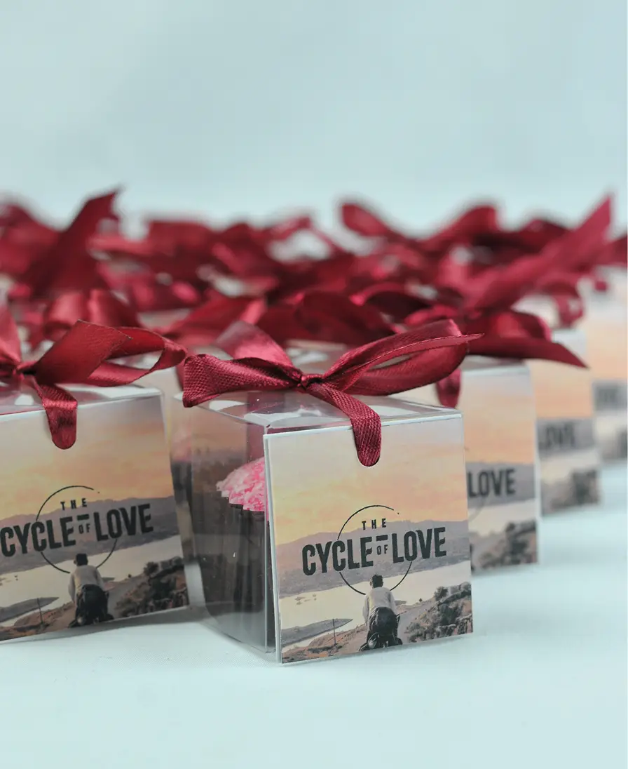 Ladoomail celebration favours tied with burgundy ribbon and swing tags printed 'The Cycle of Love'.