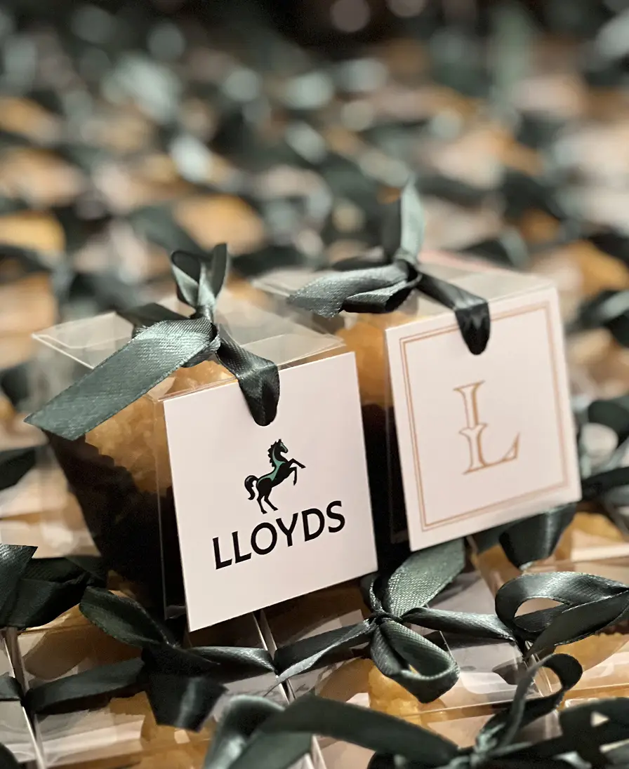 Ladoomail favours with green ribbon swing tags, softly lit.