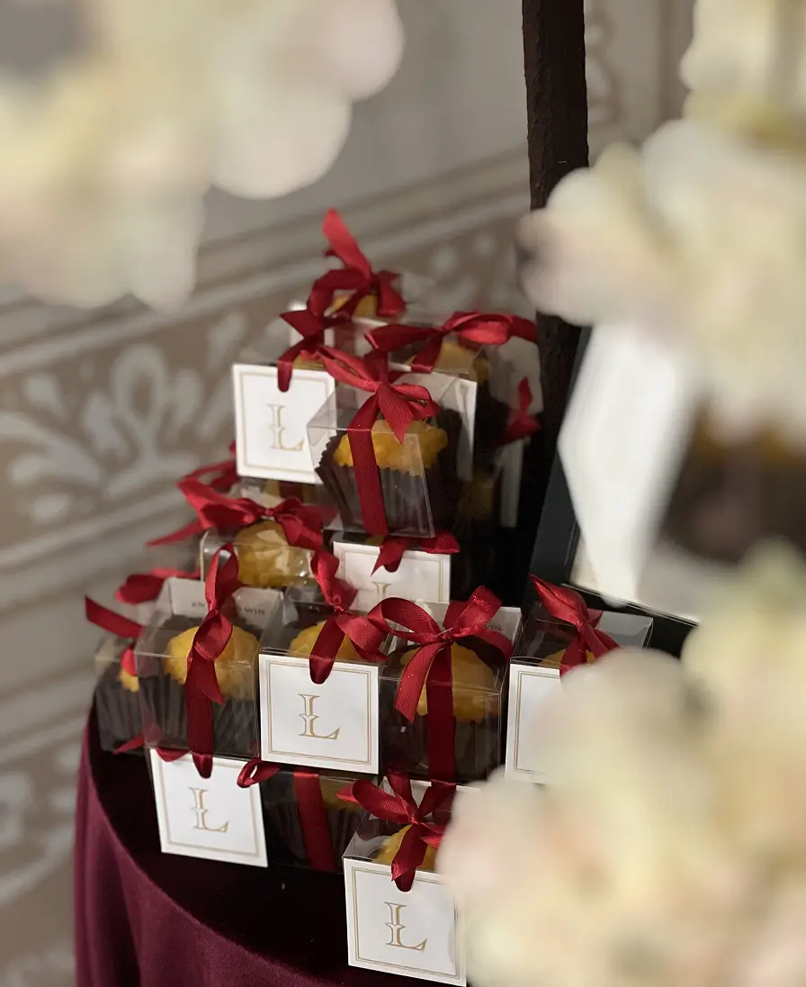 Stacked Ladoomail favours tied with red ribbon and monogrammed swing tags.