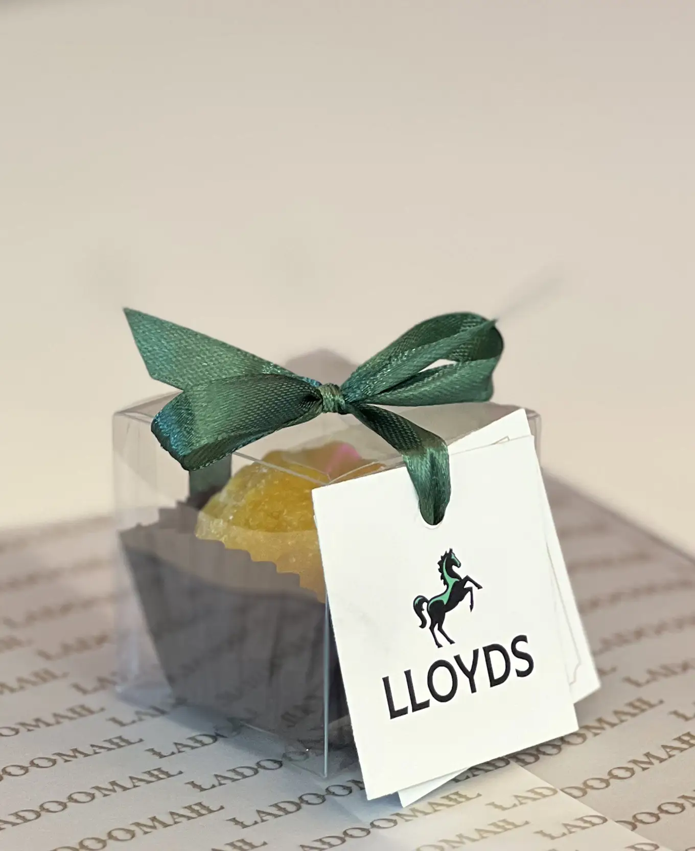 Ladoomail celebration favour with a Lloyds Bank tag and green ribbon on Ladoomail airmail packaging.
