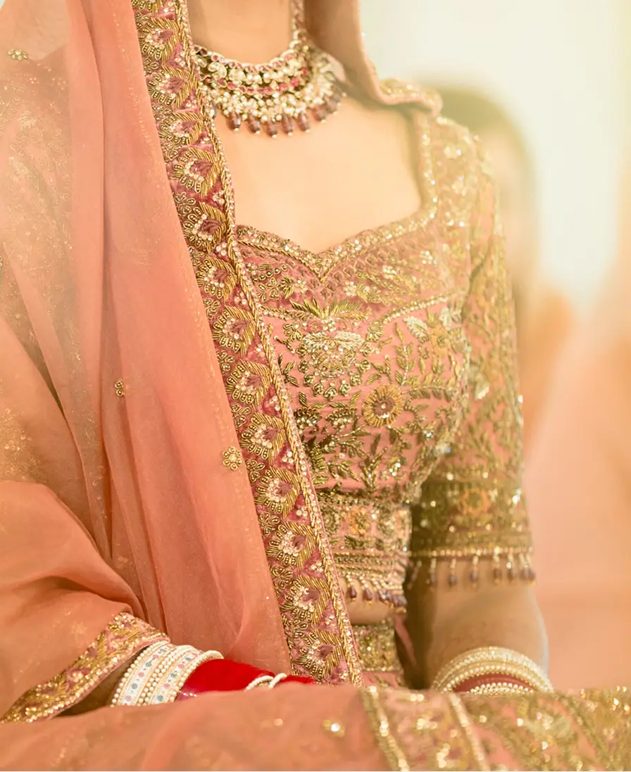 Embroidered peach and gold bridal lehenga with layered jewellery.