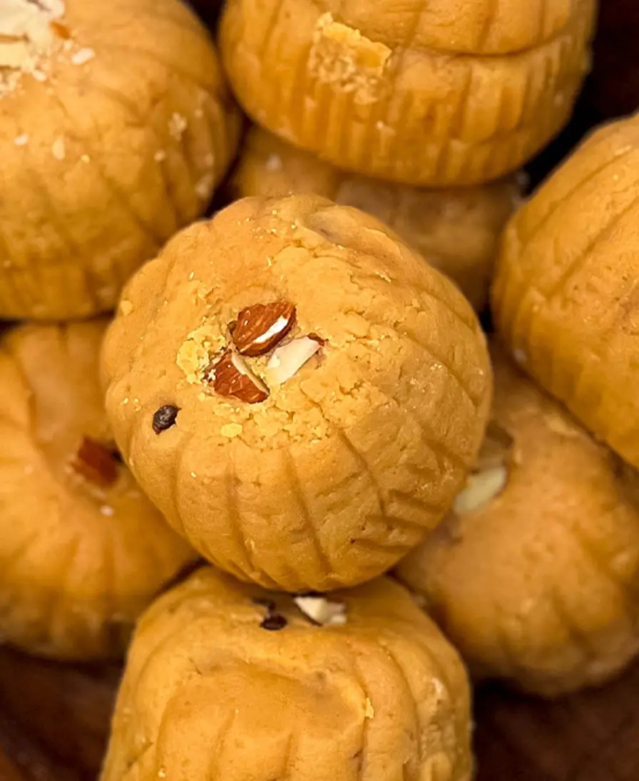 Mathura peda Close-up of handmade caramel-brown ridged Mathura peda finished with almond, in a wooden bowl.