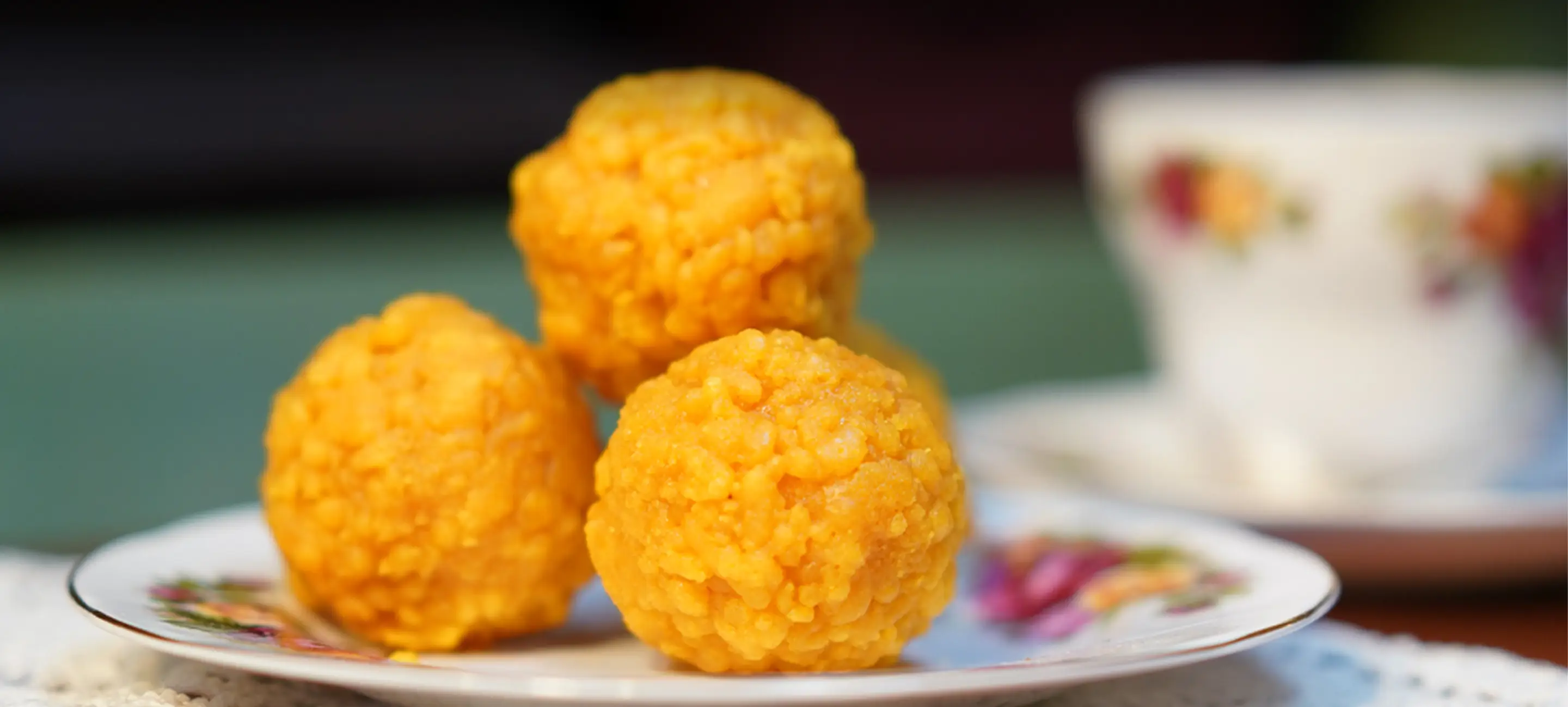 Motichoor ladoo on a vintage floral plate beside a teacup.