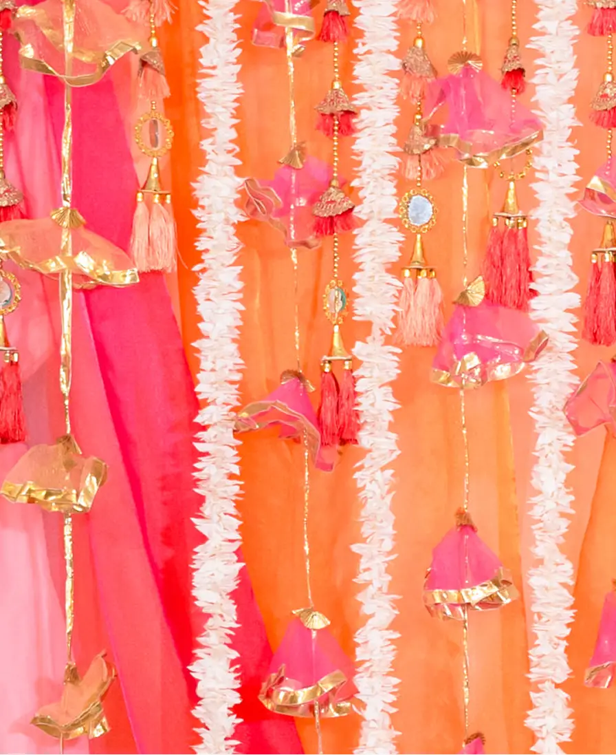 Pink, orange and gold tassel decor backdrop for a Haldi or Mehndi.