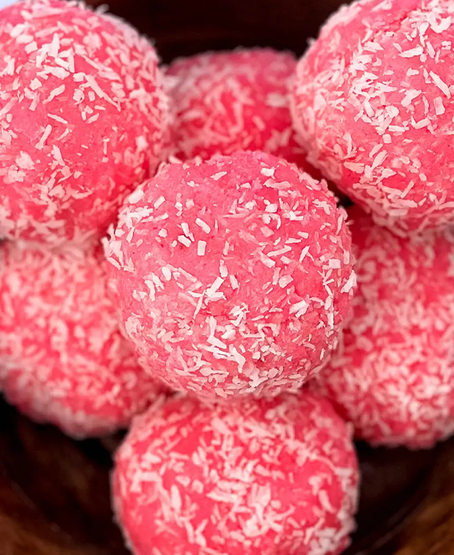Close-up of handmade pink rose coconut ladoo rolled in desiccated coconut.