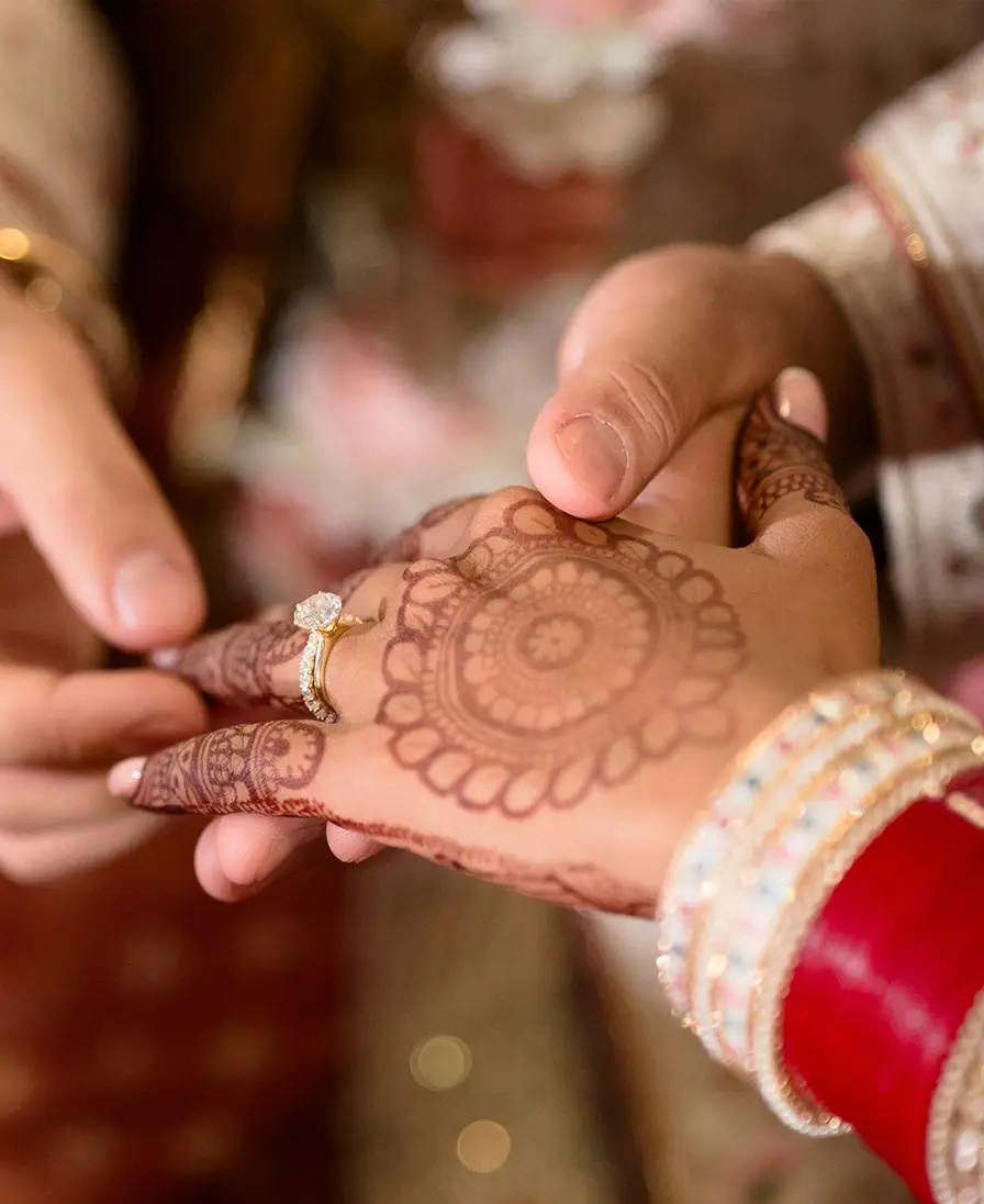 Close-up of a henna-decorated hand receiving an engagement ring.