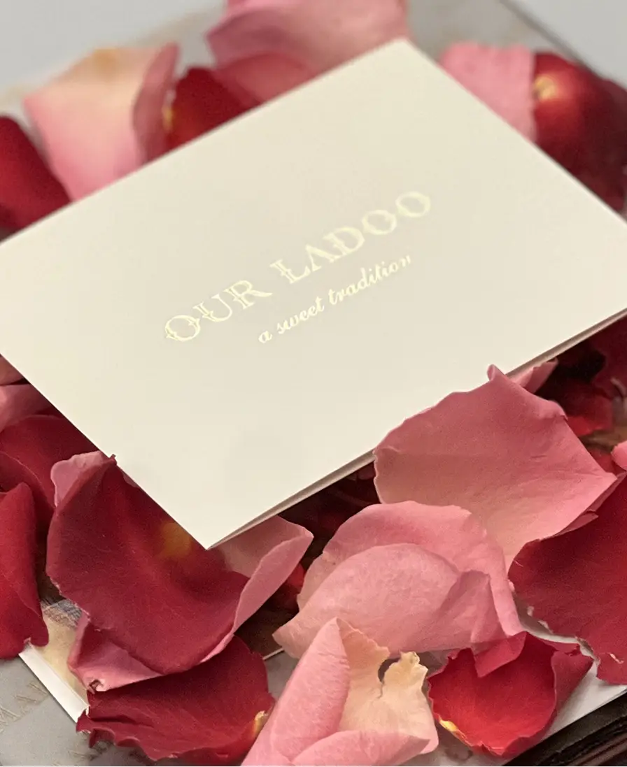 'Our Ladoo, a sweet tradition' gift card on rose petals.